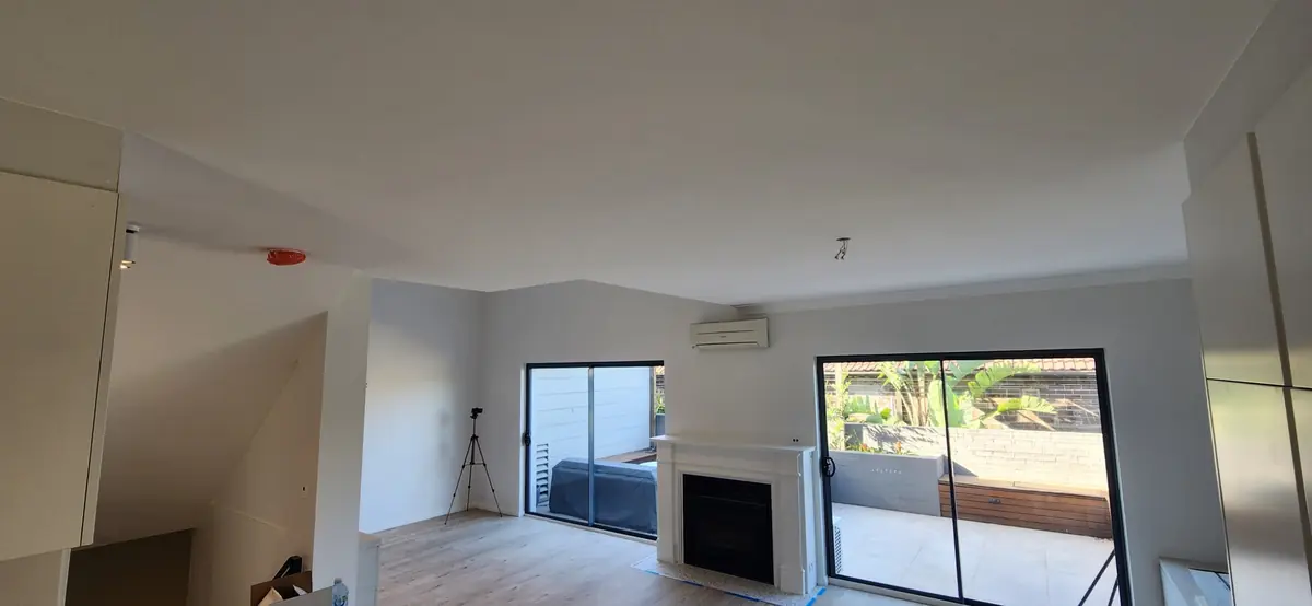 Maroubra townhouse living room after repainting, with a light wall beside the fireplace