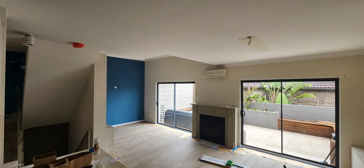 Maroubra townhouse living room before repainting, with a blue wall beside the fireplace