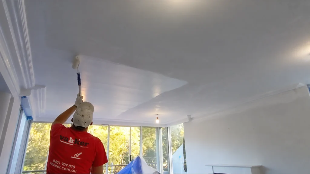 Vakker painter using a roller to paint a white ceiling in a Sydney home