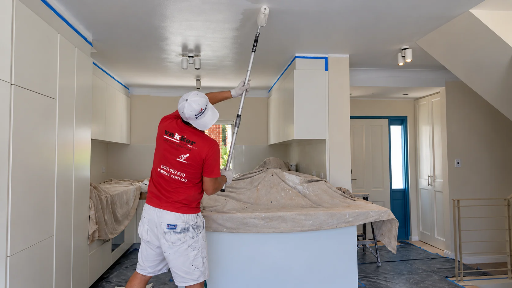 Vakker painter applying ceiling paint above a protected kitchen in a Maroubra townhouse